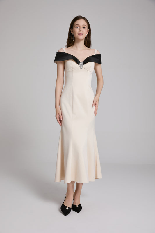 Woman wearing a white off-shoulder dress with black trim on a gray background