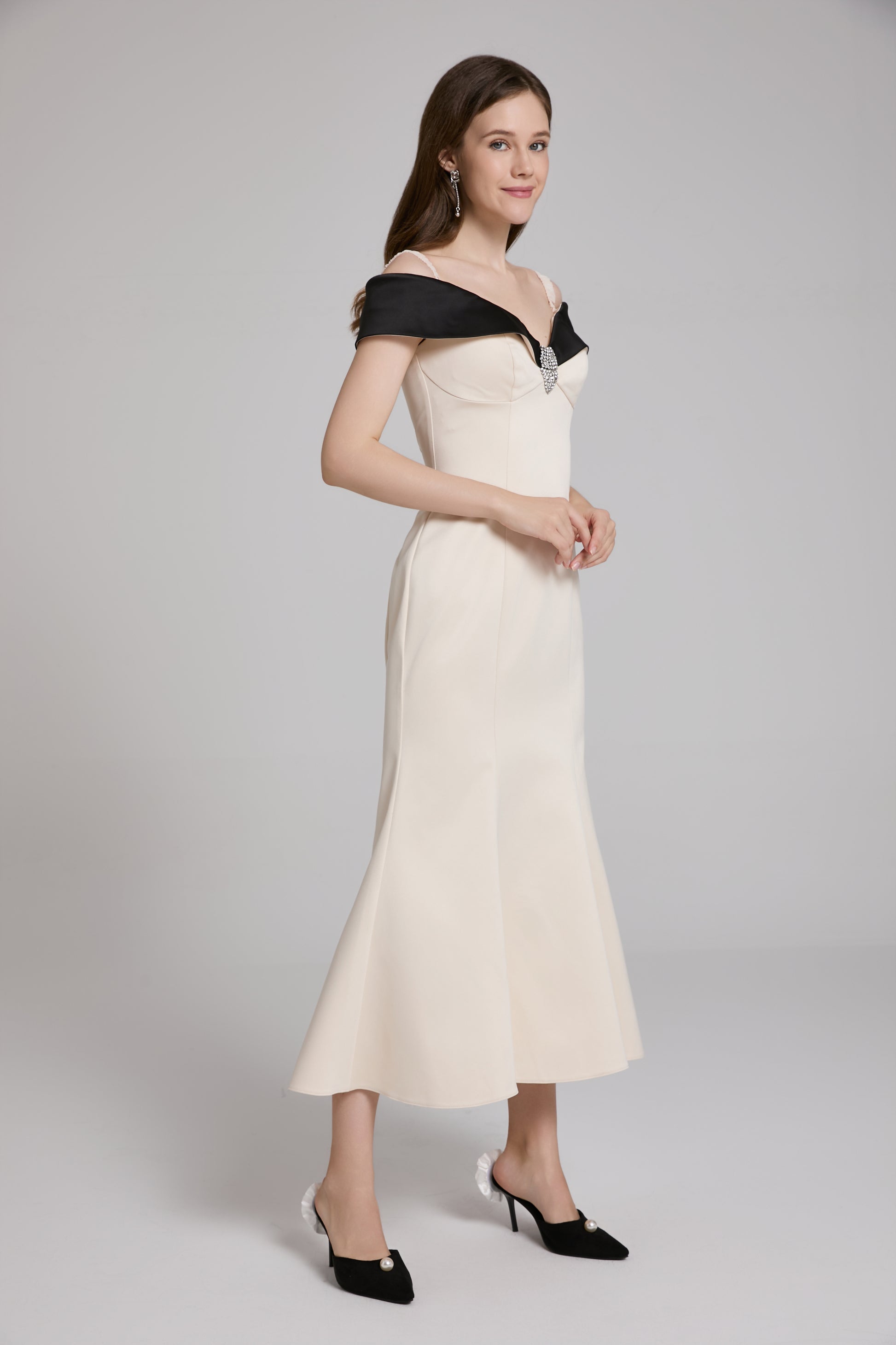 Woman wearing a black and white off-shoulder dress on a gray background