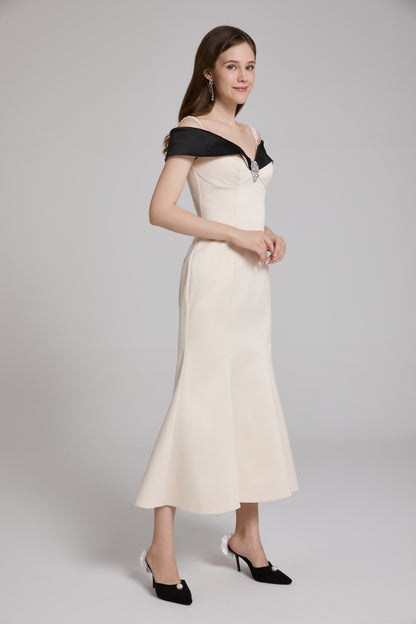 Woman wearing a black and white off-shoulder dress on a gray background