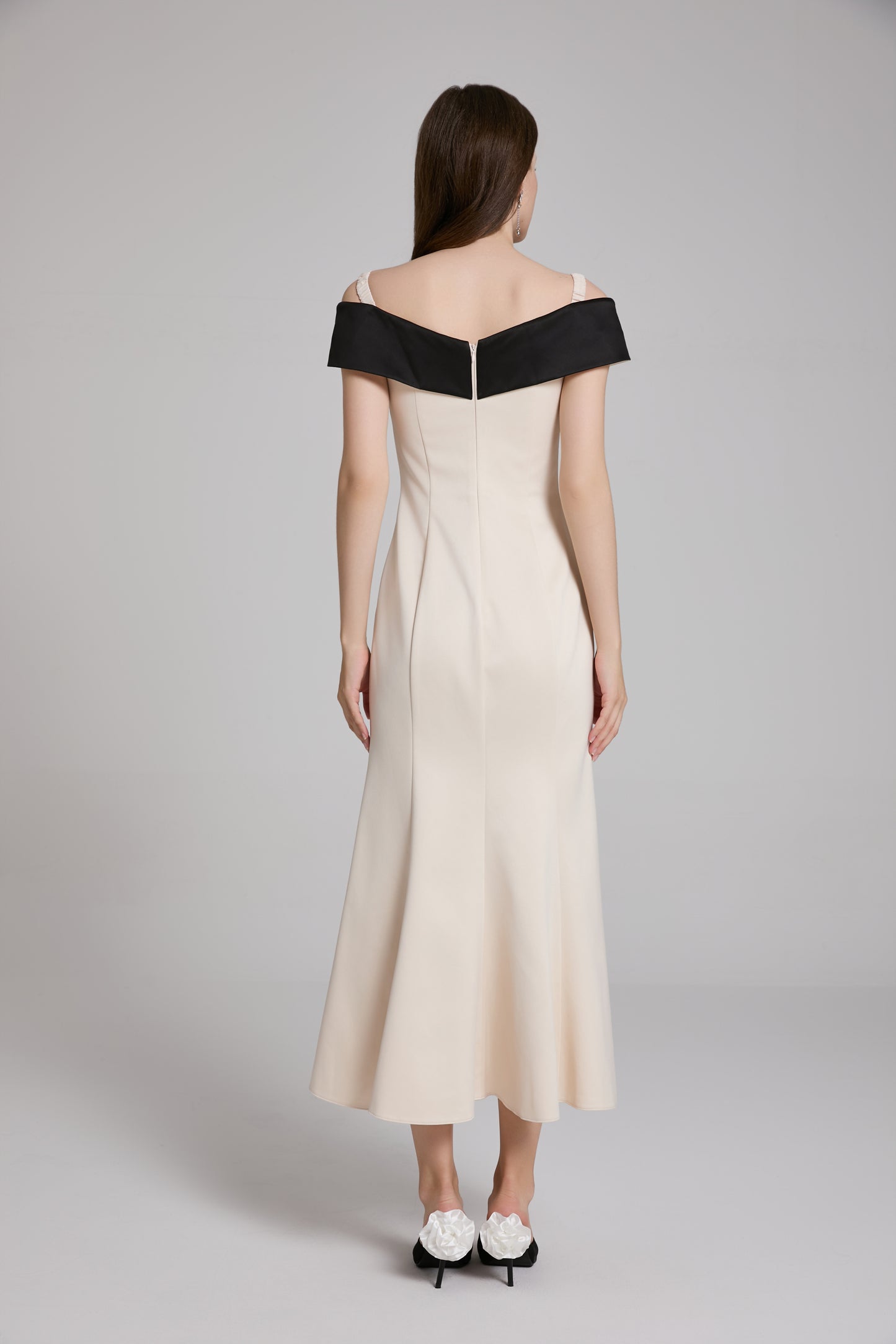 Woman wearing a white dress with black accents on a gray background