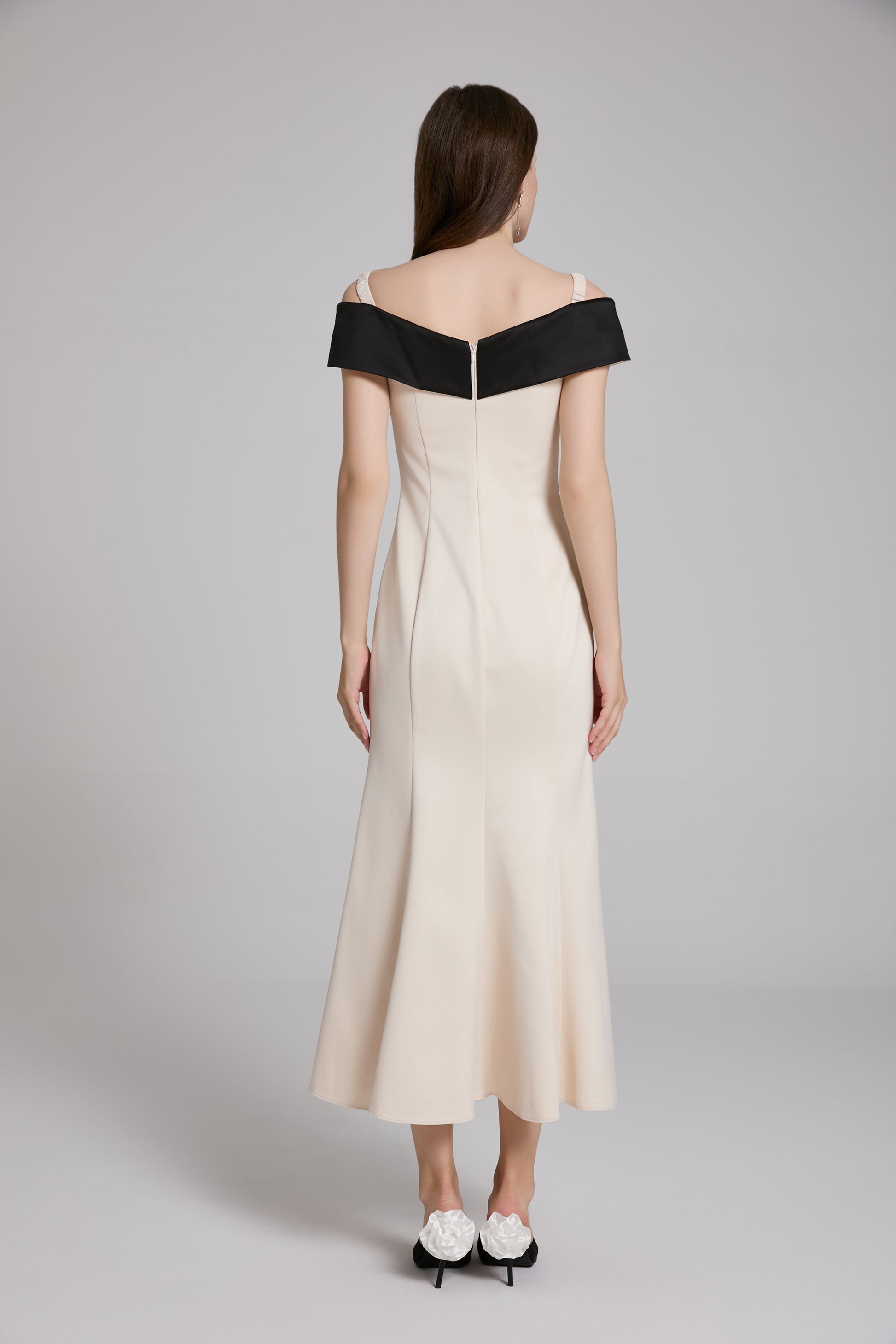 Woman wearing a white dress with black accents on a gray background