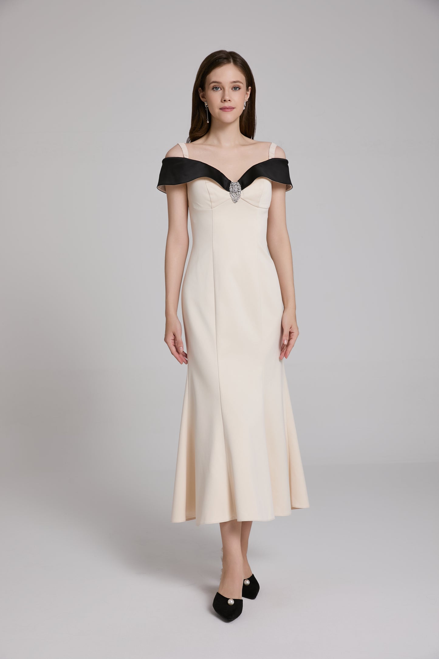 Woman wearing a white evening gown with black accents on a gray background