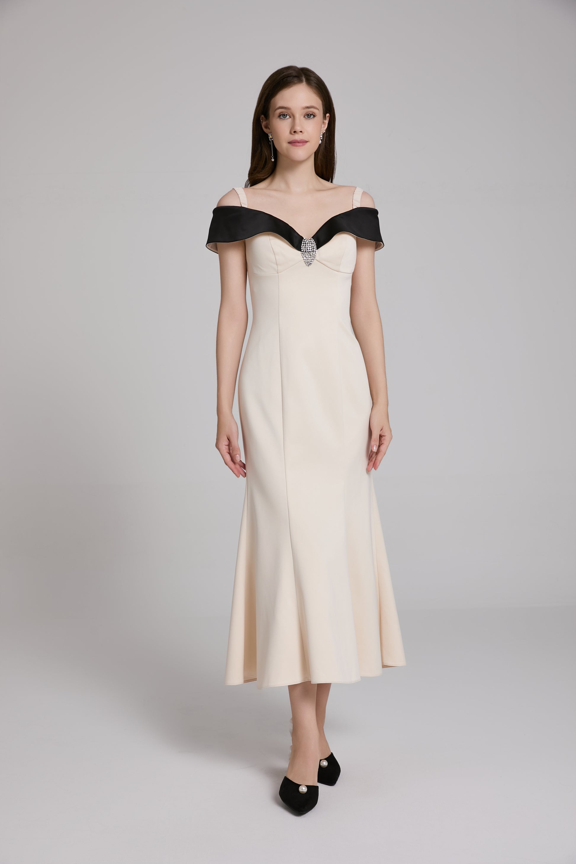 Woman wearing a white evening gown with black accents on a gray background